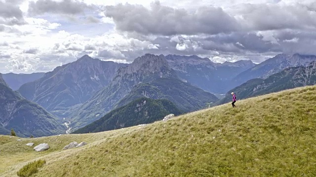空中高级女跑步者跑下草地在高山上与美丽的风景视频素材