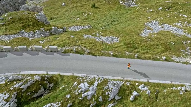 空中奔跑者在一个阳光明媚的日子里在一个高山脉的道路上奔跑视频素材