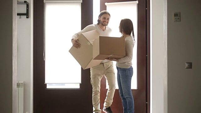 幸福的家庭夫妇抱着箱子打开门进入新房子视频素材