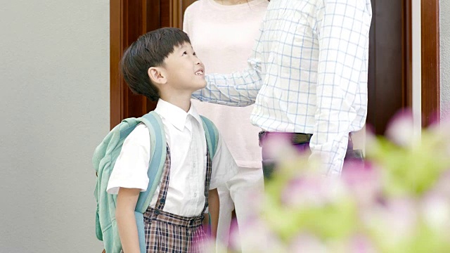 亚洲父母为儿子打开大门，走出家门去上学视频素材