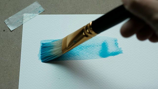 特写镜头的艺术家画一个蓝色矩形在水彩使用画笔在水彩纸200 GSM。视频素材