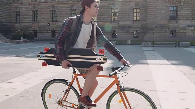 一个年轻人骑着自行车去练习滑板视频素材