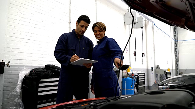 一组机械师在一家汽车修理厂做检查清单视频素材