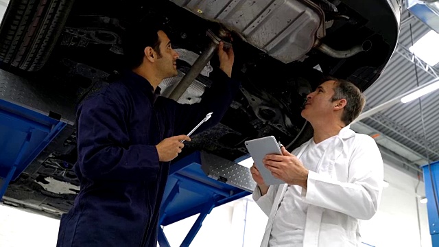 经理和机械师在谈论车底需要修理的零件视频素材