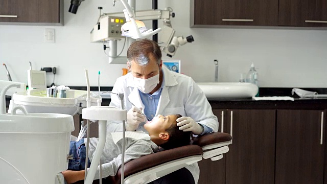 儿科牙科医生正在检查他的小病人的牙齿视频素材