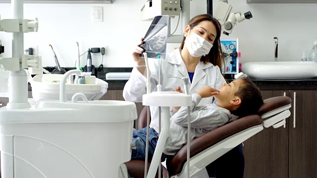 友善的儿科牙医和她的小病人谈话，给他看一张x光片视频素材