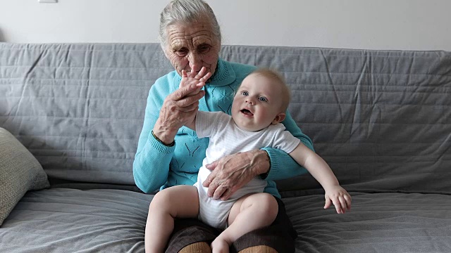 一位带着海象的老祖母坐在沙发上，怀里抱着一个小孙子。视频下载