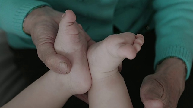 一个婴儿的脚在一个祖母皱纹的手的特写。视频素材