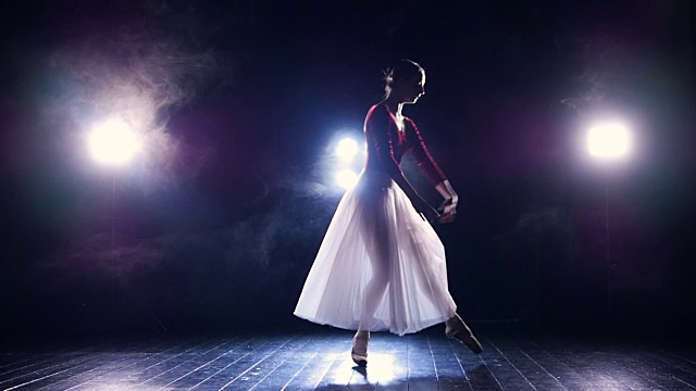 一个在聚光灯前慢慢跳舞的芭蕾舞演员。视频素材