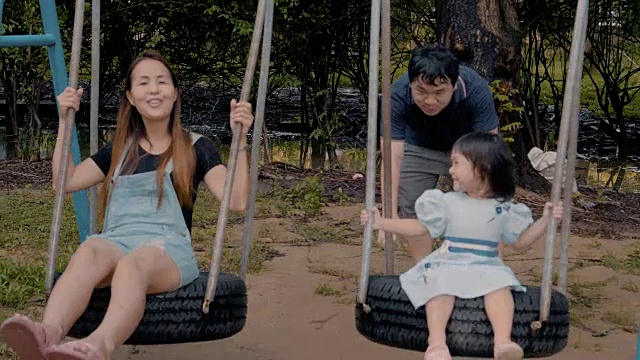亚洲家庭与一个小女孩荡秋千享受在公共公园视频素材