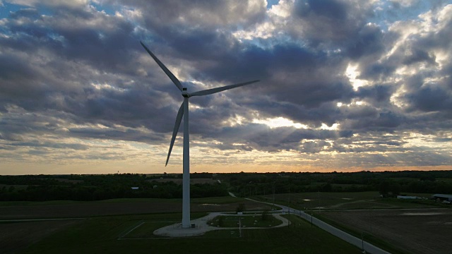 巨大的风力涡轮机在日落时在壮观的天空下转动视频素材