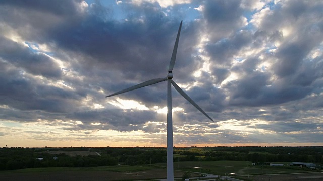 巨大的风力涡轮机在日落时在壮观的天空下转动视频素材