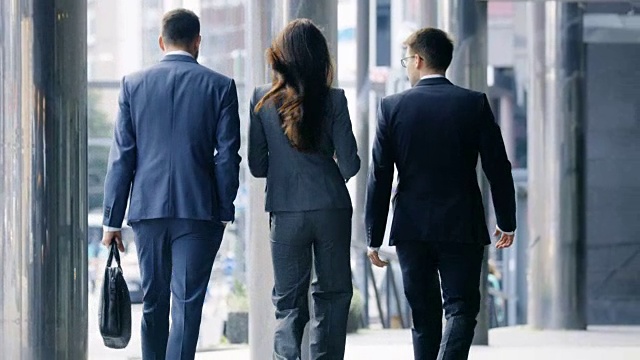 在中央商务区行走的三位商务人士的后视图。视频素材