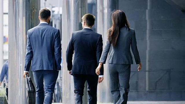 在中央商务区行走的三位商务人士的后视图。视频素材
