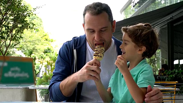 儿子在冰淇淋店和爸爸分享冰棒视频素材