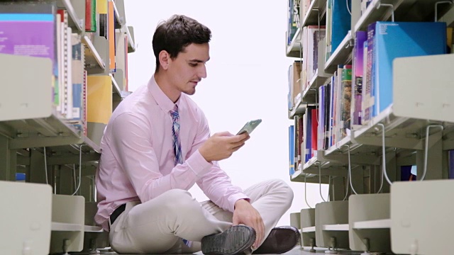 年轻人在图书馆用智能手机搜索视频下载
