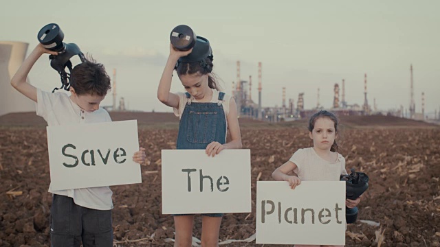 保存植物。一群拿着牌子、带着防毒面具的孩子站在炼油厂附近视频素材