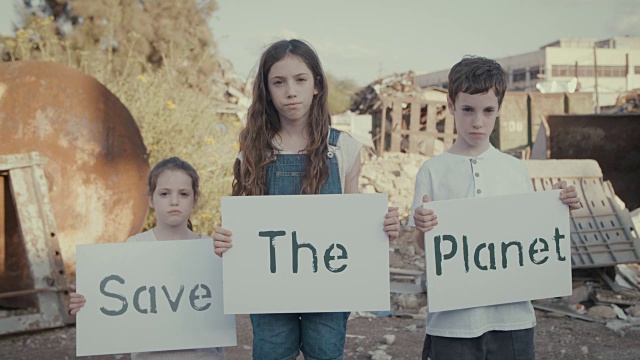拯救地球。小孩子们举着标语站在一个巨大的垃圾场旁边视频素材