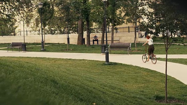 自行车女子骑着自行车在夏季公园后视图。女子自行车公园视频素材
