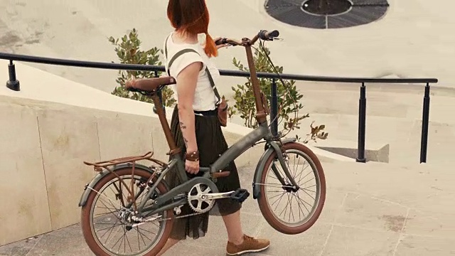 骑自行车的女人走下楼梯，手里拿着自行车。女子自行车的城市视频素材