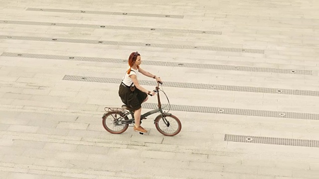 夏日里，女自行车手在广场上的柏油路上骑着自行车视频素材