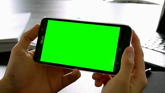 摄影:在办公桌上用绿色屏幕为色度键的手机拍摄视频素材