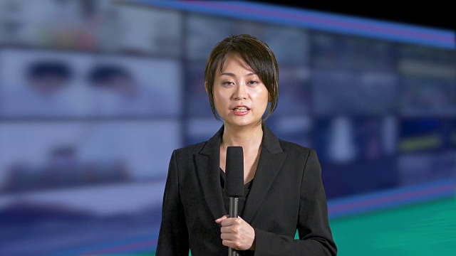 新闻女主播在演播室里，背景是一排排的屏幕视频下载