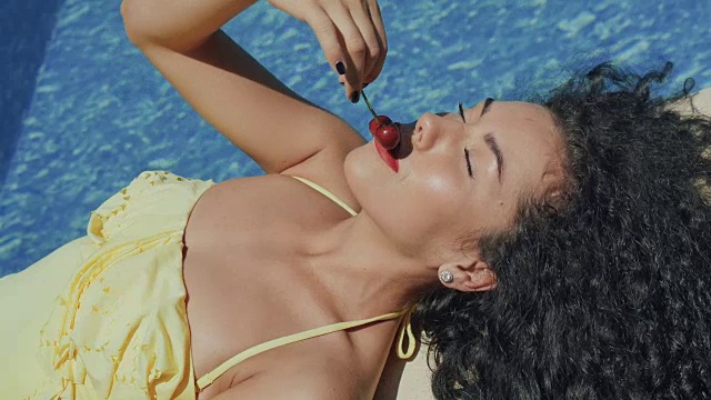 美丽的女人与红唇性感触摸樱桃的脸附近的游泳池视频下载