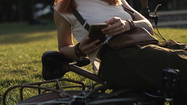 自行车女人在夏季公园用手机打字短信视频素材