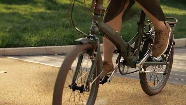 消除自行车轮子。近景年轻女子骑自行车在路公园视频素材