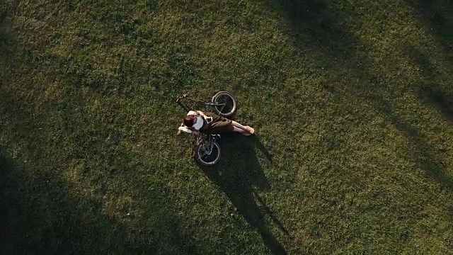 Top view女子自行车躺在城市公园的绿色草地上使用手机视频素材