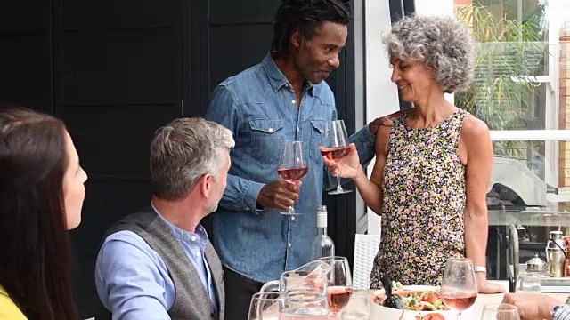 成熟的女人和男人与一群朋友在晚宴上举起酒杯视频下载