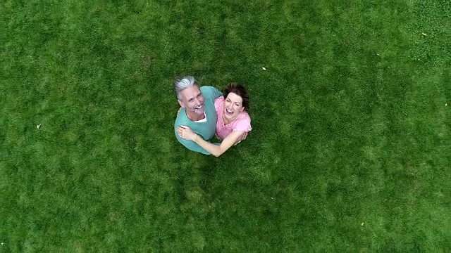 一对成熟的夫妇站在绿色的草坪上，对着镜头微笑着挥手视频素材