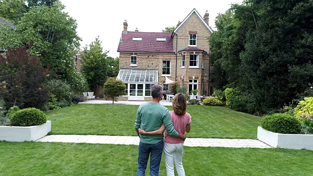 成熟的夫妇抱着对方看房子和建筑外观的观点视频素材