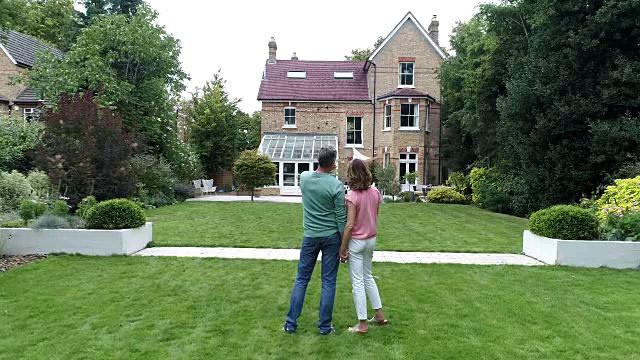 成熟的夫妇站在后花园，欣赏他们的家与建筑俯视图视频素材