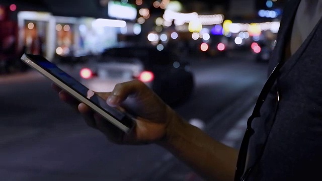 近距离观察女人的手，在她的智能手机上写信息与汽车灯光背景。视频素材