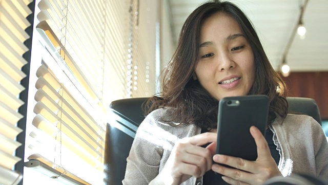 亚洲年轻女子看着智能手机和微笑视频素材