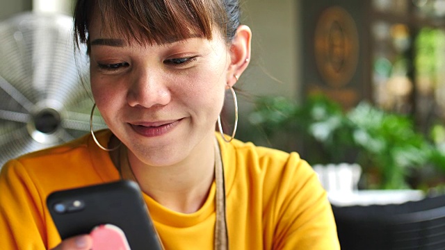 亚洲年轻女子看着智能手机和微笑视频下载