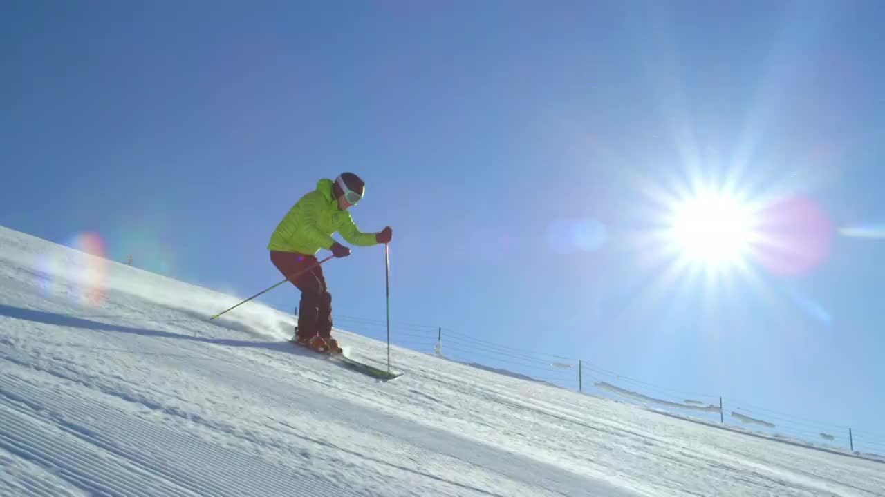 追踪慢动作:滑雪者在早晨刚修整过的雪道上快速转弯视频购买