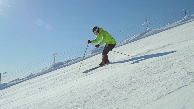 慢动作专业滑雪者在下雪的冬日里从阳光明媚的山上斜坡上滑雪视频素材