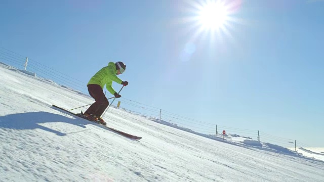在阳光明媚的冬日里，业余的年轻滑雪者沿着斜坡滑雪视频素材