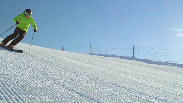 慢动作跟踪完美的雪道与滑雪者雕刻下斜坡视频购买