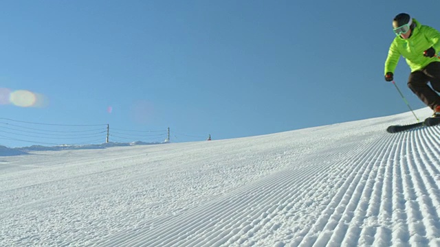 慢动作跟踪完美的雪道与滑雪者雕刻下斜坡视频素材