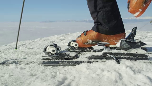慢动作接近:滑雪者在雪道上用滑雪靴进入滑雪板绑带视频素材