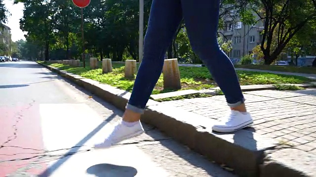 录像显示一名女性的双腿正在过马路。匿名的画面。视频下载
