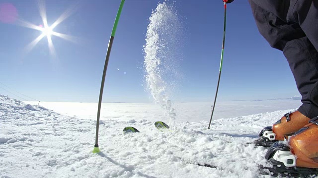 慢动作鱼眼:在一个阳光明媚的日子里，滑雪者从滑雪板上取出刚落下来的雪视频素材