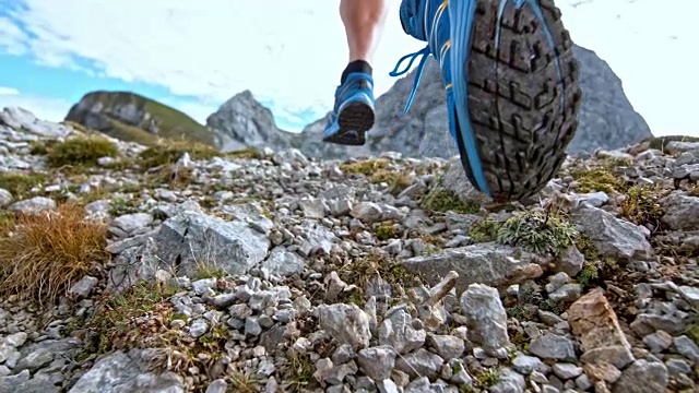 一名男性跑步者的脚，在高山小径上撒碎石视频素材