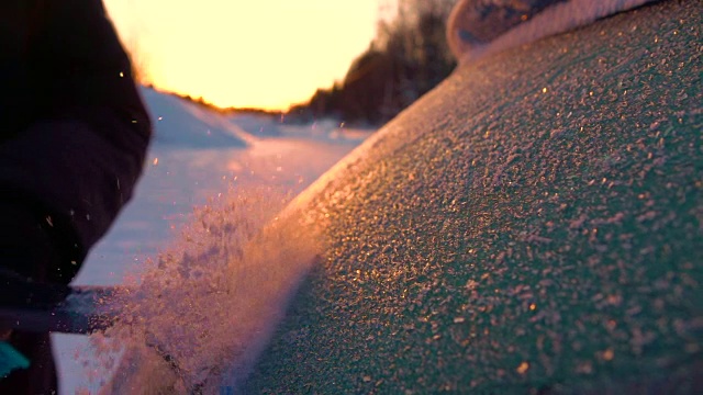 慢镜头近景在冬日日出时从车窗上刮下闪闪发光的霜视频素材