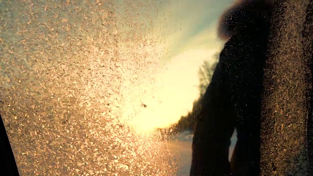 慢镜头:在冬日日出时，移除车窗上结冰的花朵视频素材
