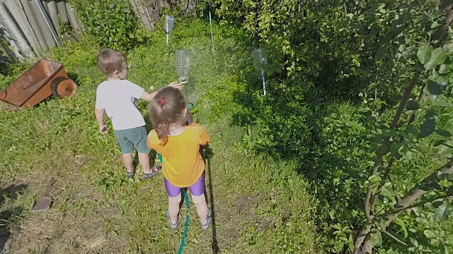 孩子们在乡间小屋的院子里给植物浇水视频素材